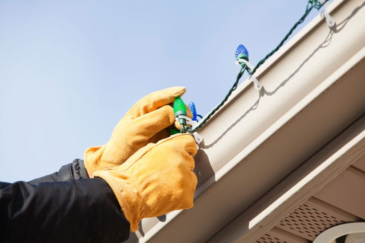 Closeup of Gloved Hands Hanging Lights on Gutters